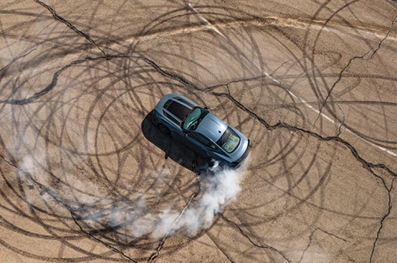 An overhead shot of a Mustang® Coupe doing donuts and smoking tires on a closed course
