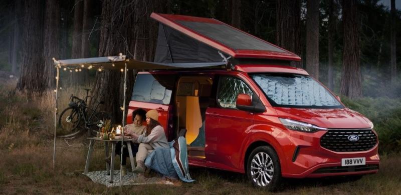 Image depicting two Transit Custom Nugget owners sitting outside their Nugget under the canopy roof enjoying a meal.