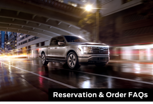 Reservation FAQ. An F-150 Lightning drives down a street at night.
