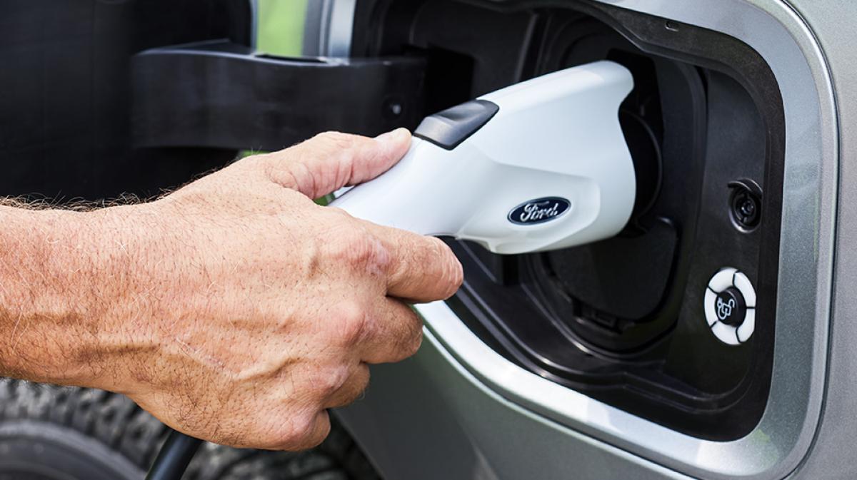 A CCS1 charger being plugged into the port of an all-electric Ford model.