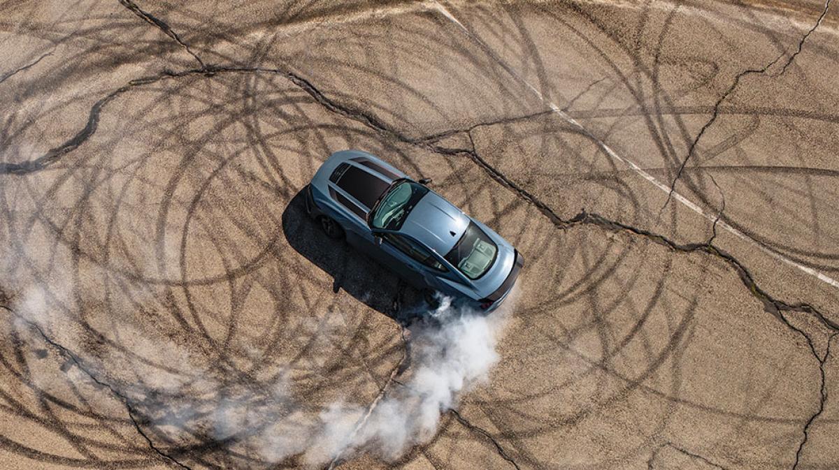 An overhead shot of a Mustang® Coupe doing donuts and smoking tires on a closed course
