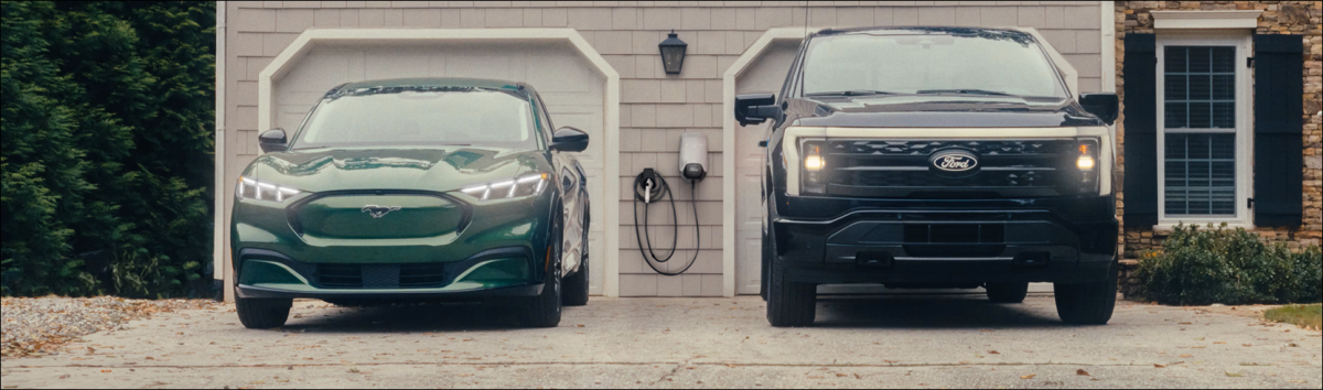 A Ford F-150 Lightning and Mustang Mach-E parked outside a home.